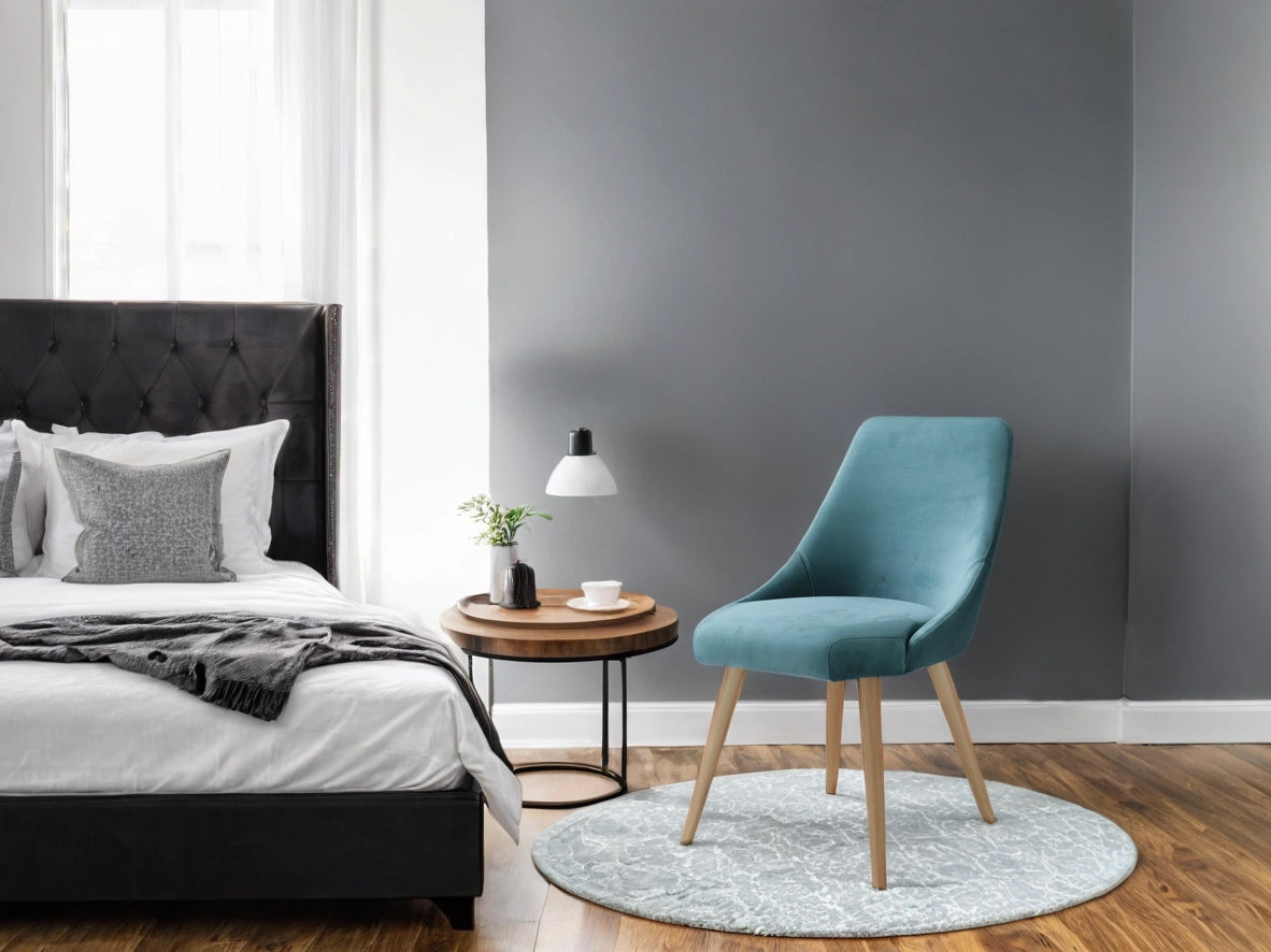 Modern bedroom with a bed, blue Alba  chair, and side table.