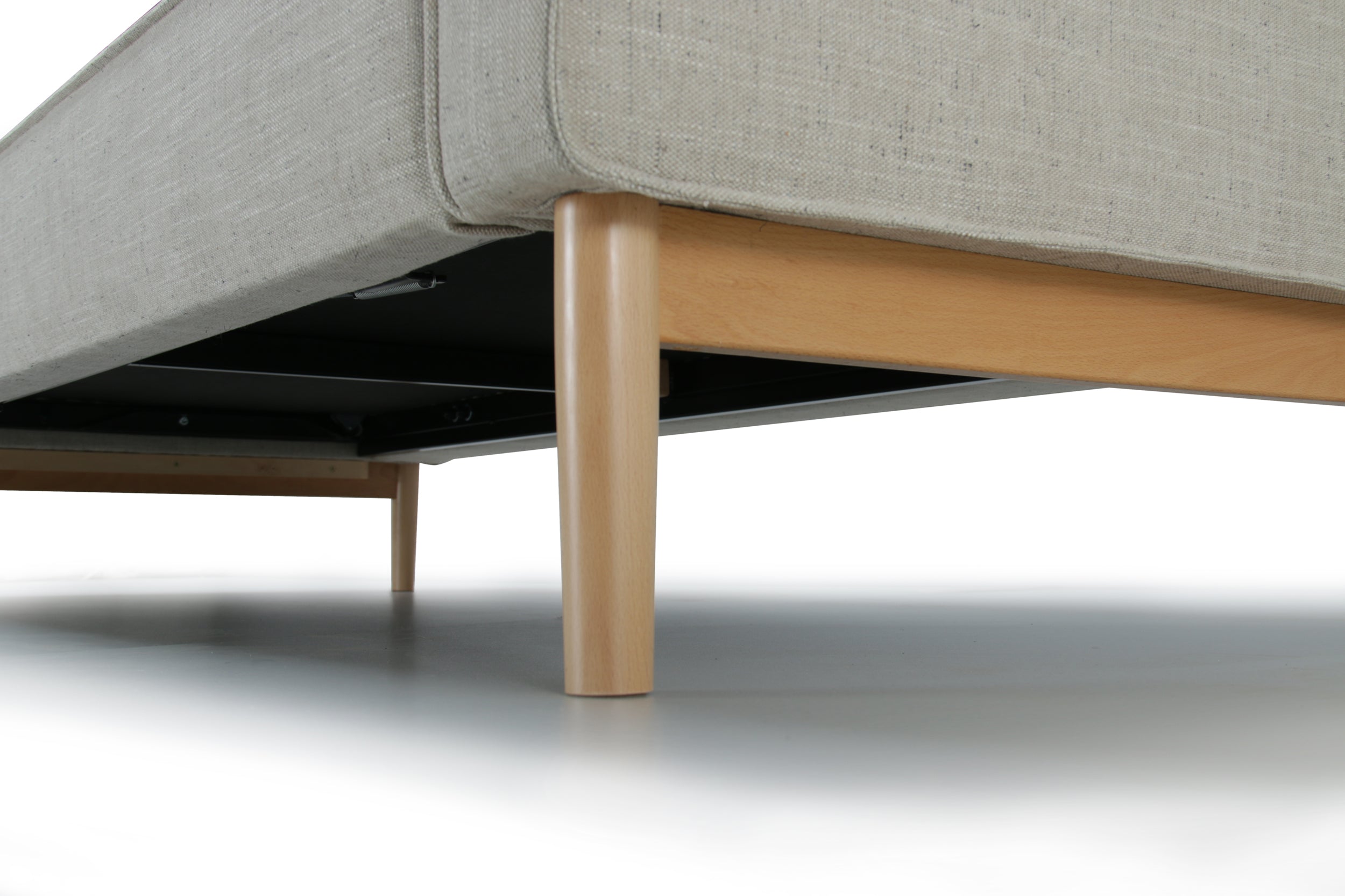 Wooden legs close view of white Alpine sofa bed with upholstered armrest on a white background.