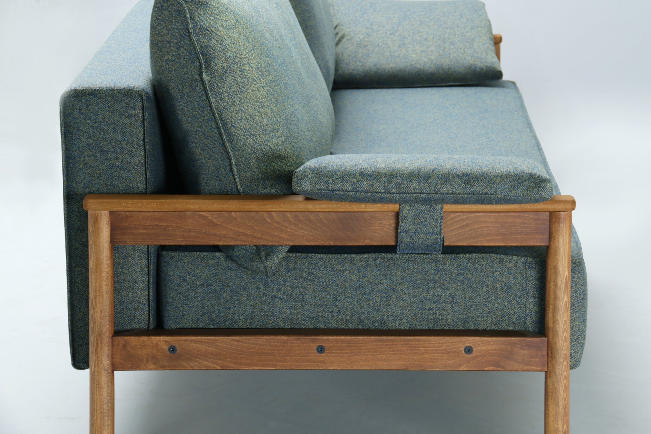 Side view of green Alpine sofa bed, with wooden armrest on a white background.