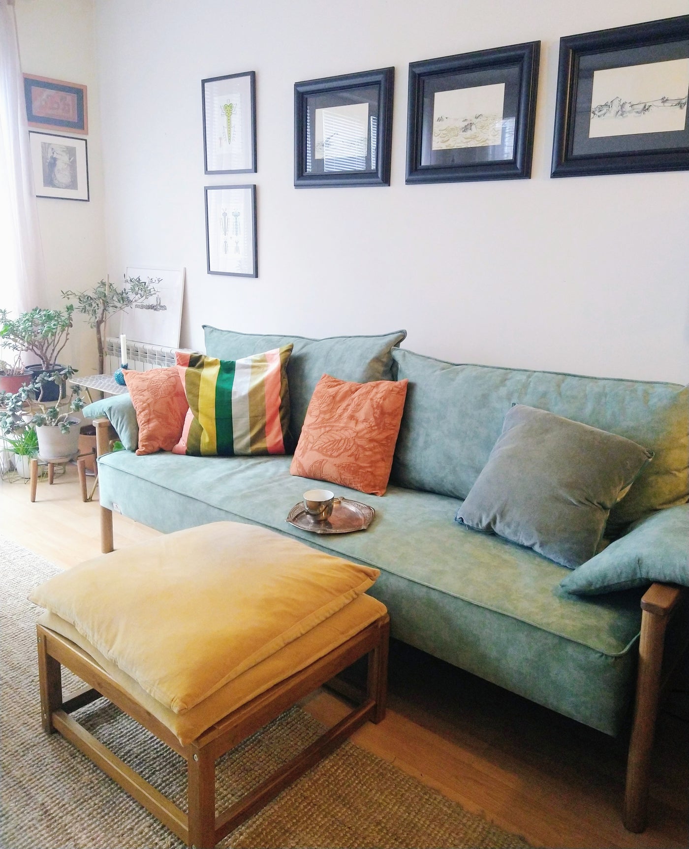 Light blue Alpine sofa bed with colorful cushions in a living room setting.