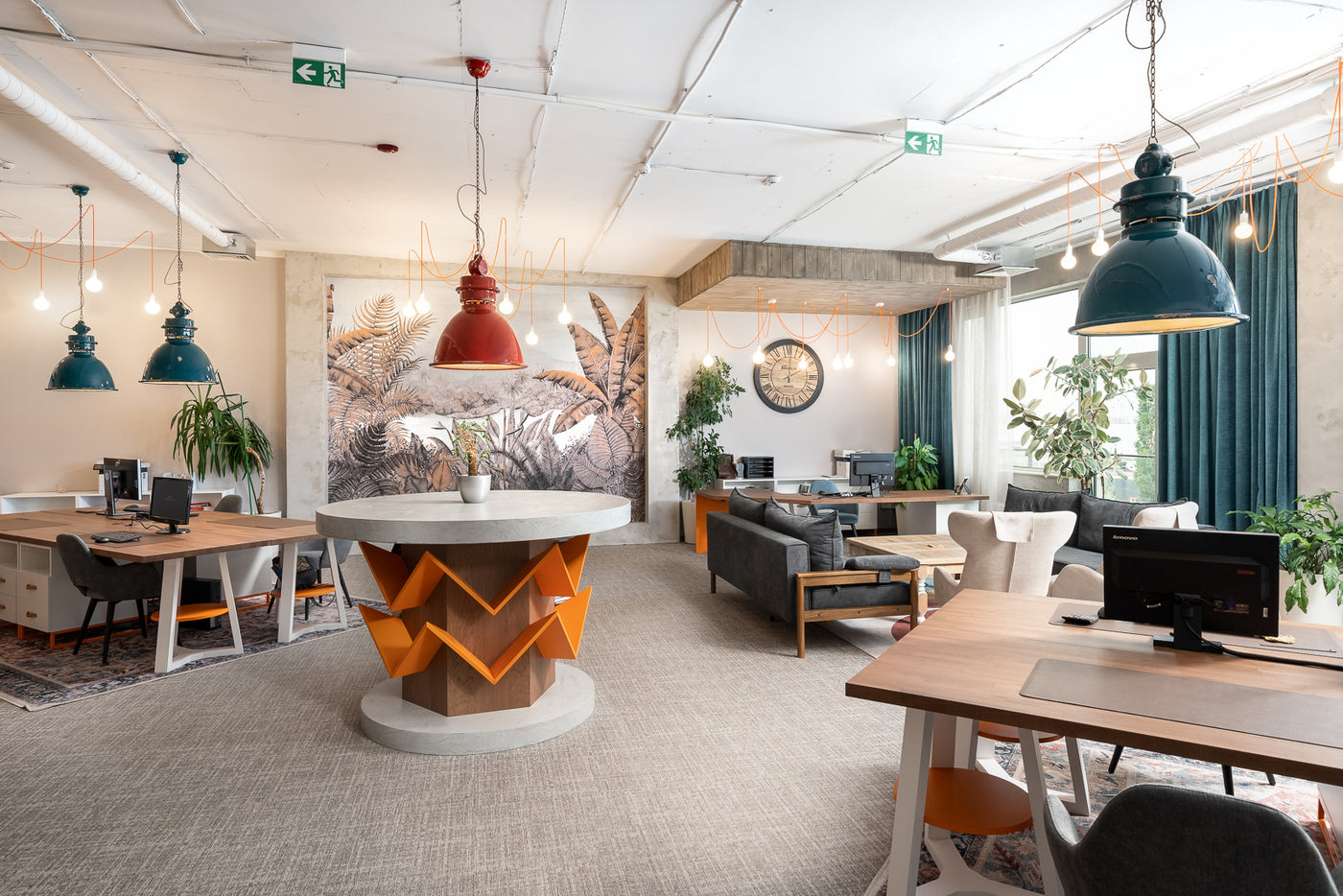 Modern office space with Alpine sofa bed and a central island table and various workstations.