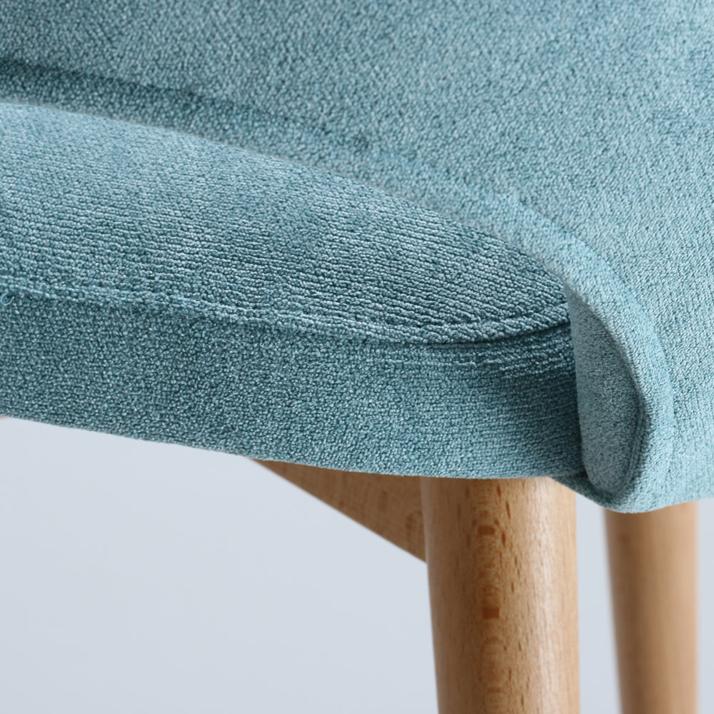 Close-up of a teal fabric Andre chair with wooden legs on a white background