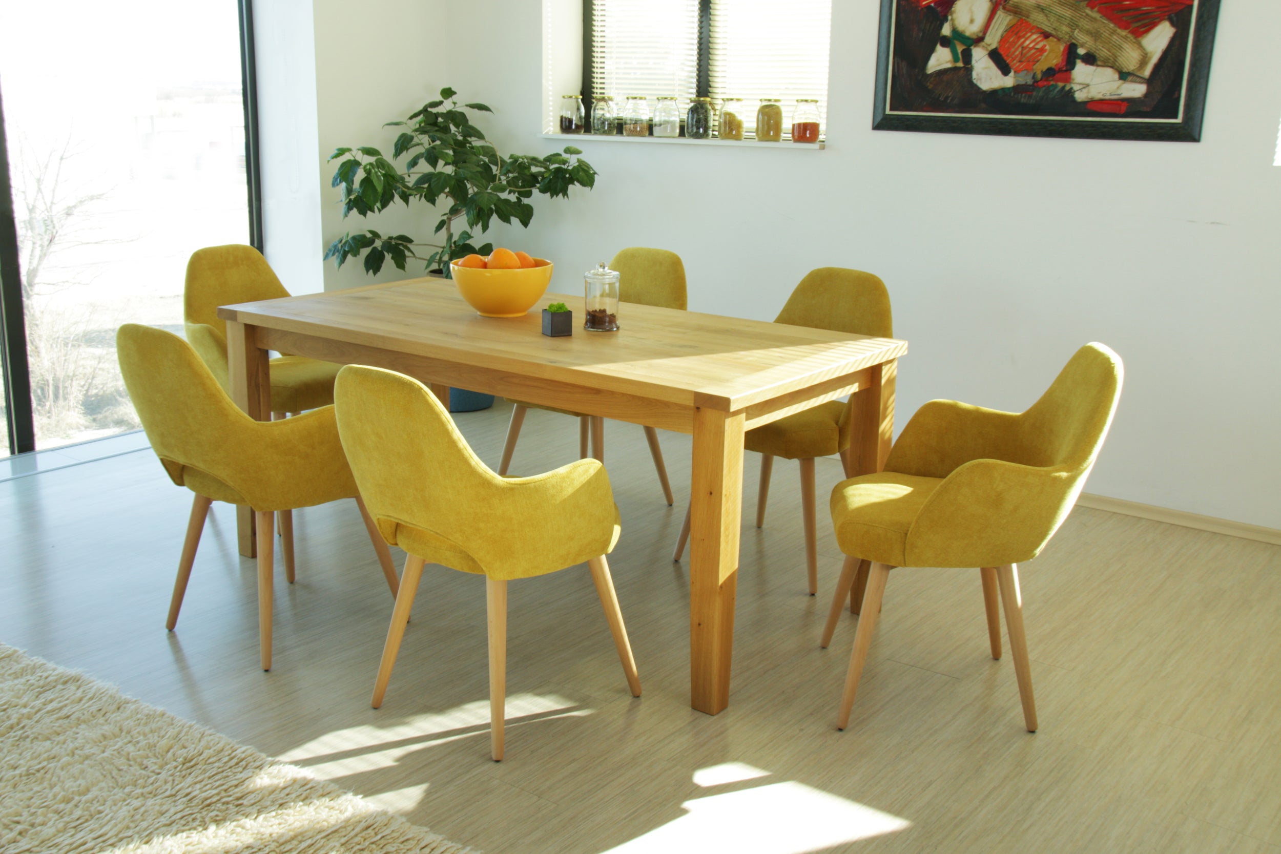 Dining area with wooden table and yellow Andre chairs in a bright room.
