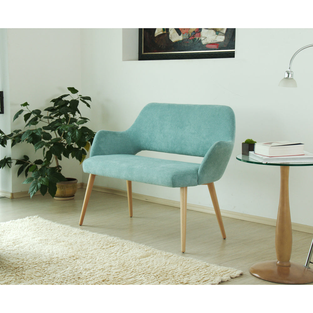 Teal Andre sofa in a living room setting with a plant and small table.