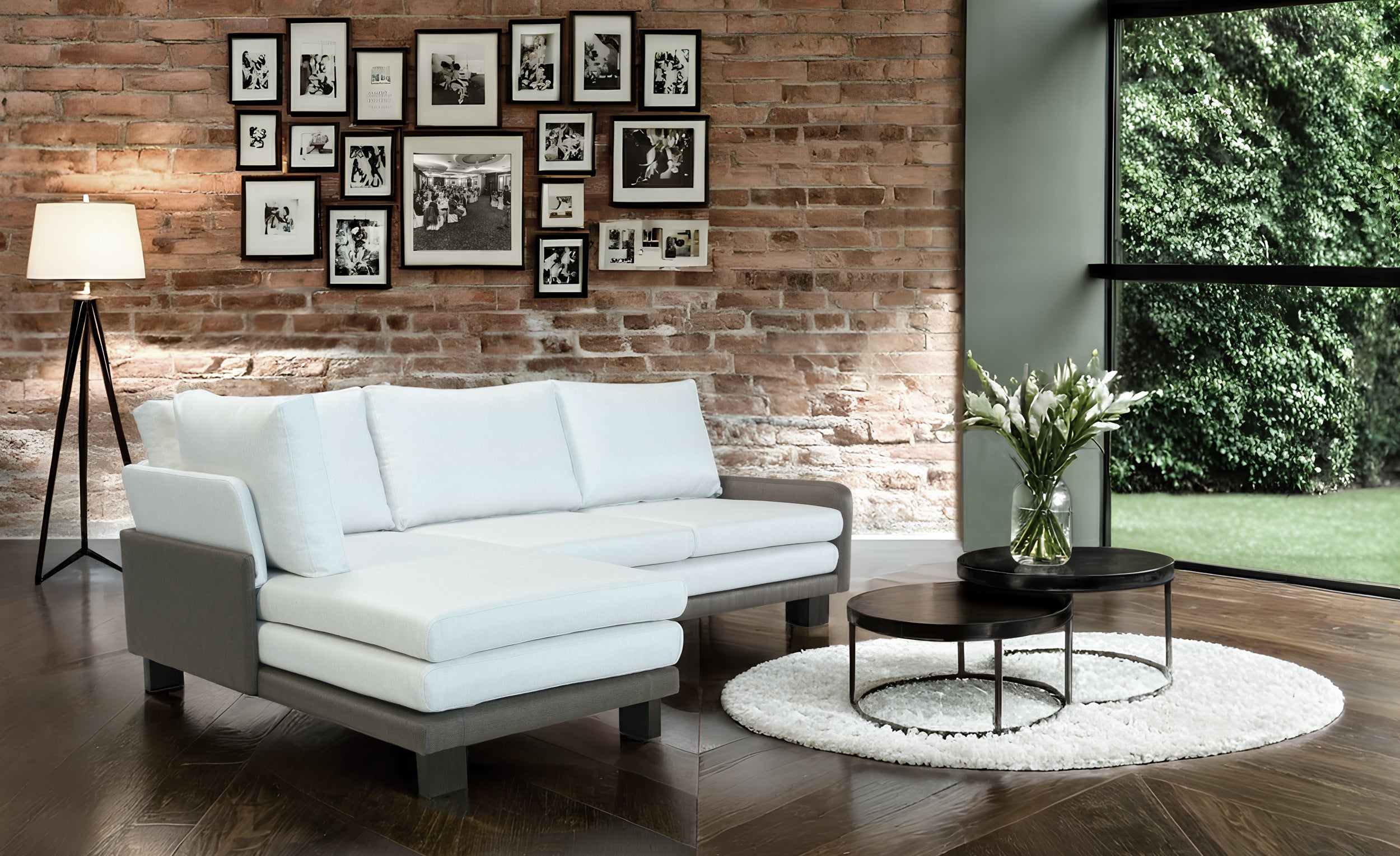 Modern living room with white B12 sofa, round coffee table, and framed pictures on brick wall.
