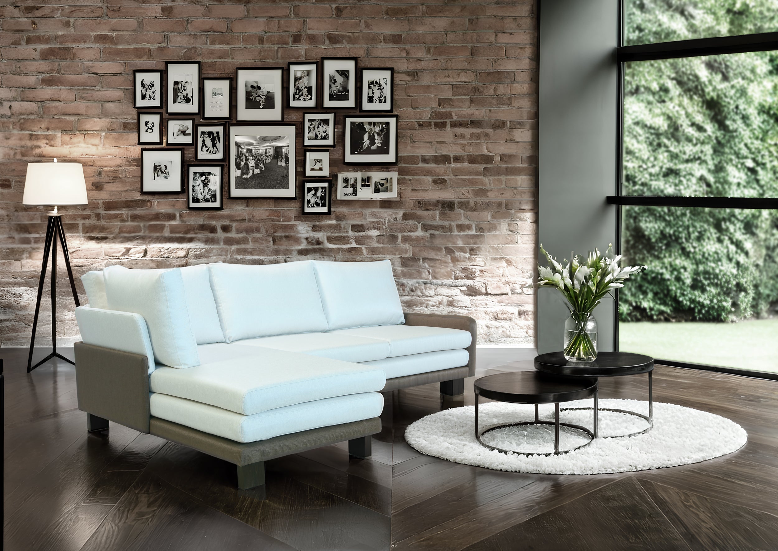 Modern living room with white B12 sofa, round coffee table, and framed pictures on brick wall.