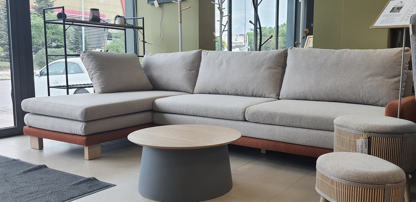 Gray sectional sofa B12 with wooden legs in a room with large windows.