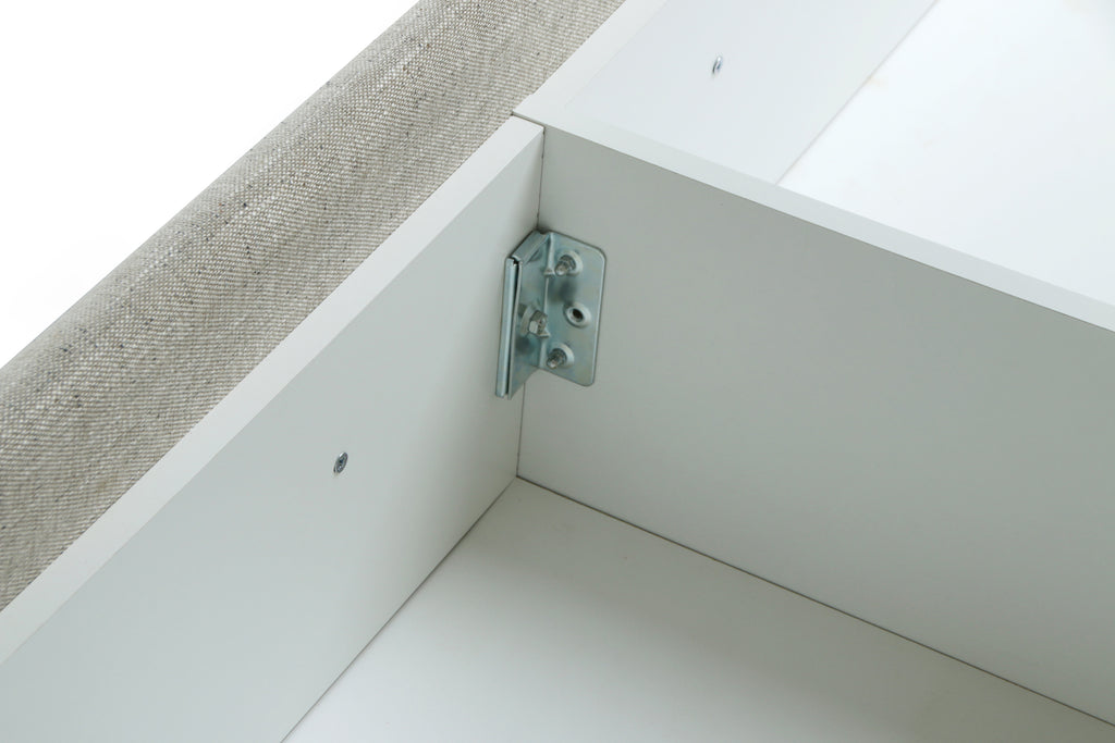 Metal bracket on a white and beige corner of a upholstered bed.