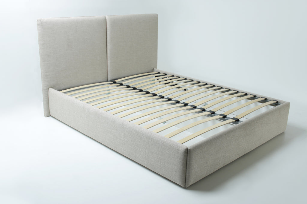 A large  beige upholstered bed frame with a tall headboard and wooden slats, shown on a white background.