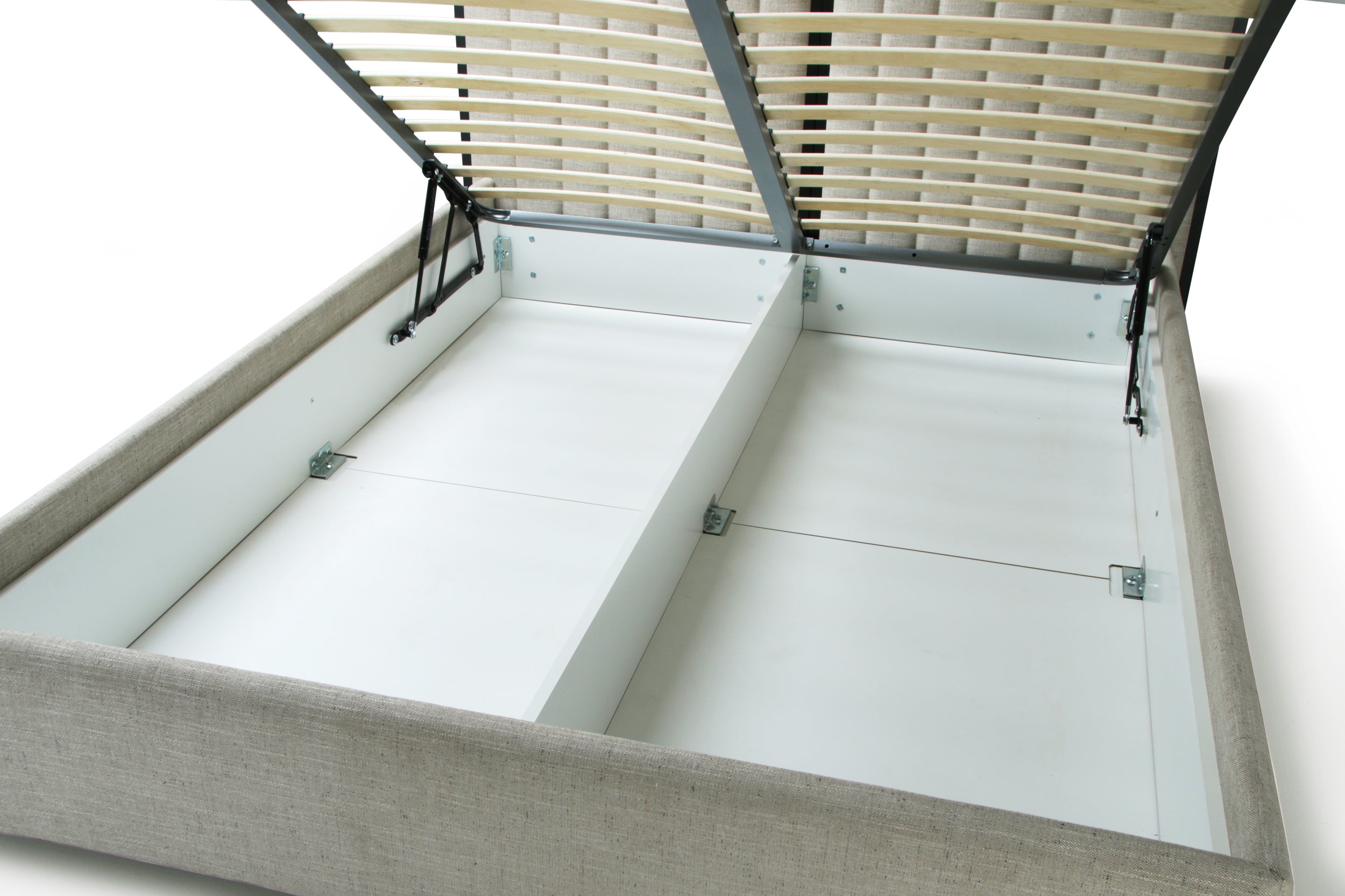 A close-up of a bed frame with the lift-up slatted lid open, showing the light gray upholstered sides, white storage compartments, and beige slats inside.