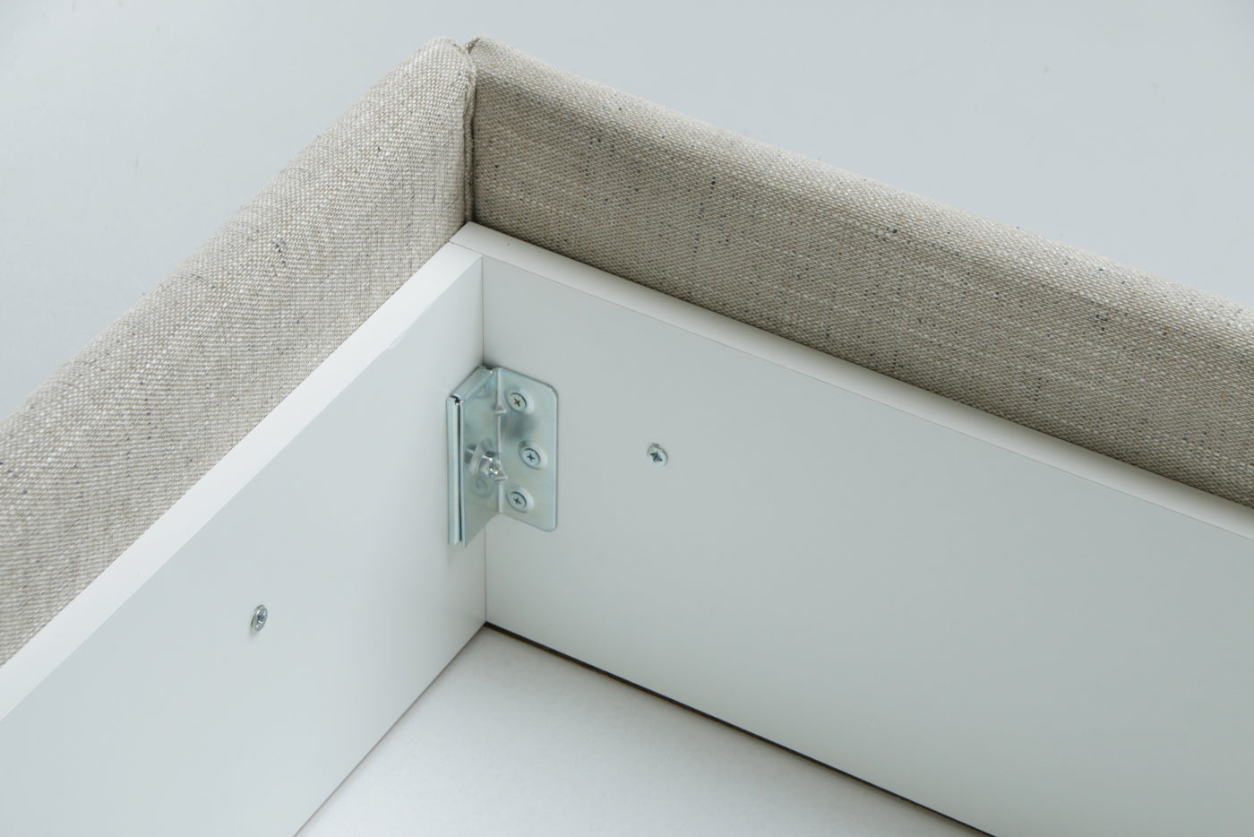 Metal bracket on a white and beige corner of a bed chest.