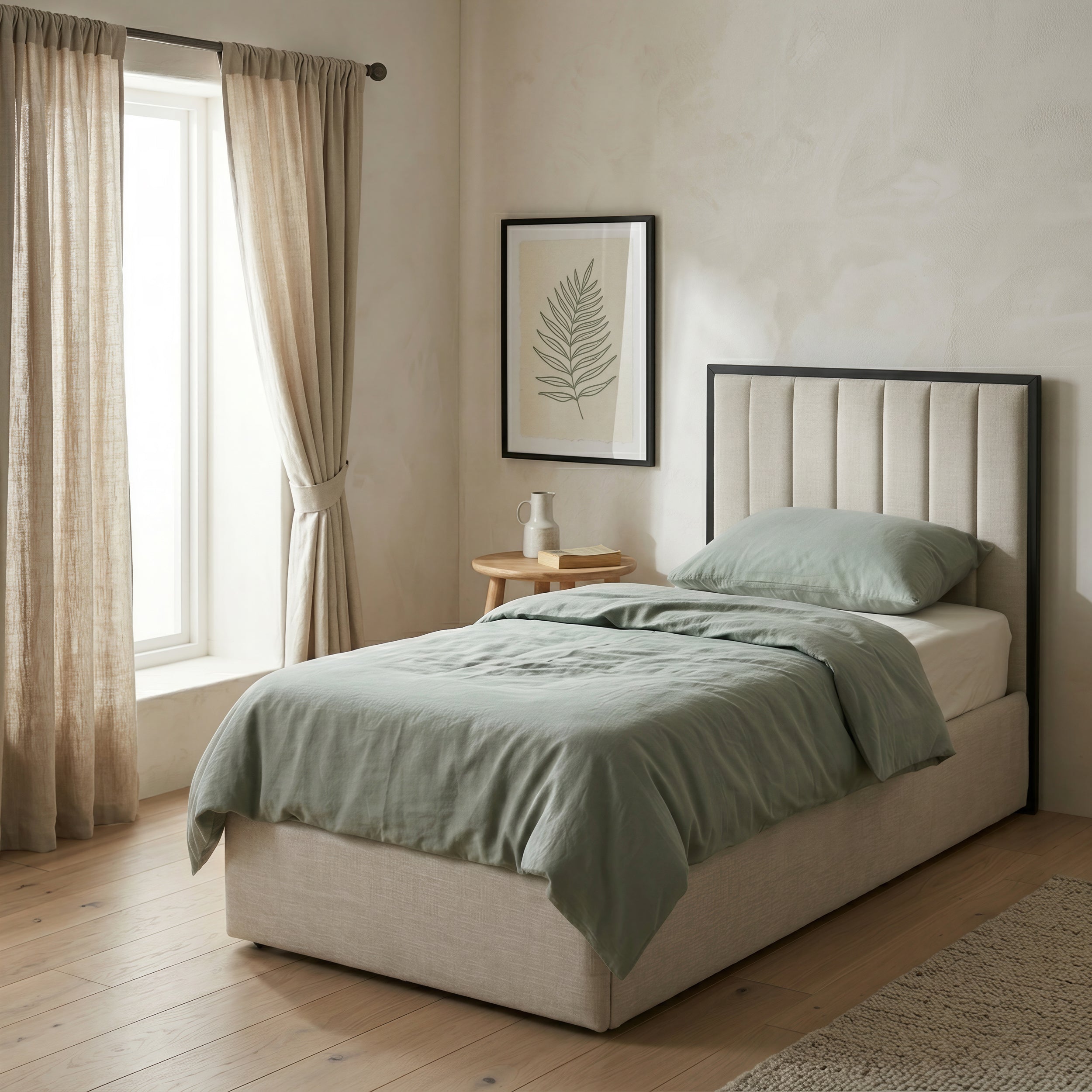 Neatly made bed with green bedding in a bedroom setting and upholstered headboard.
