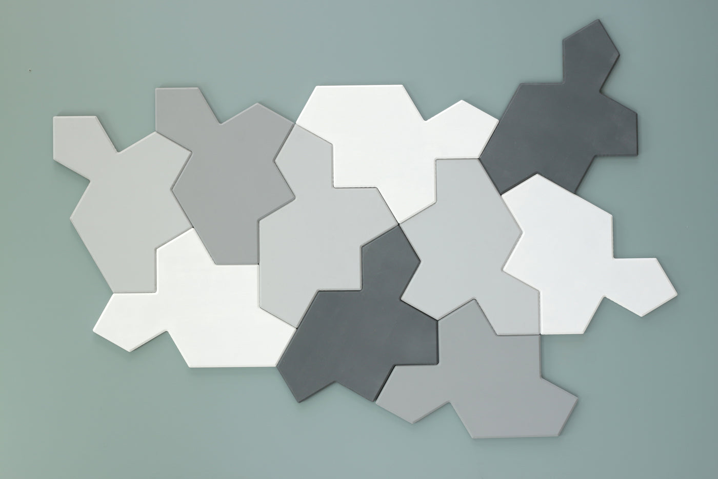 Chiral aperiodic monotile tiles in gray and white on a green  background
