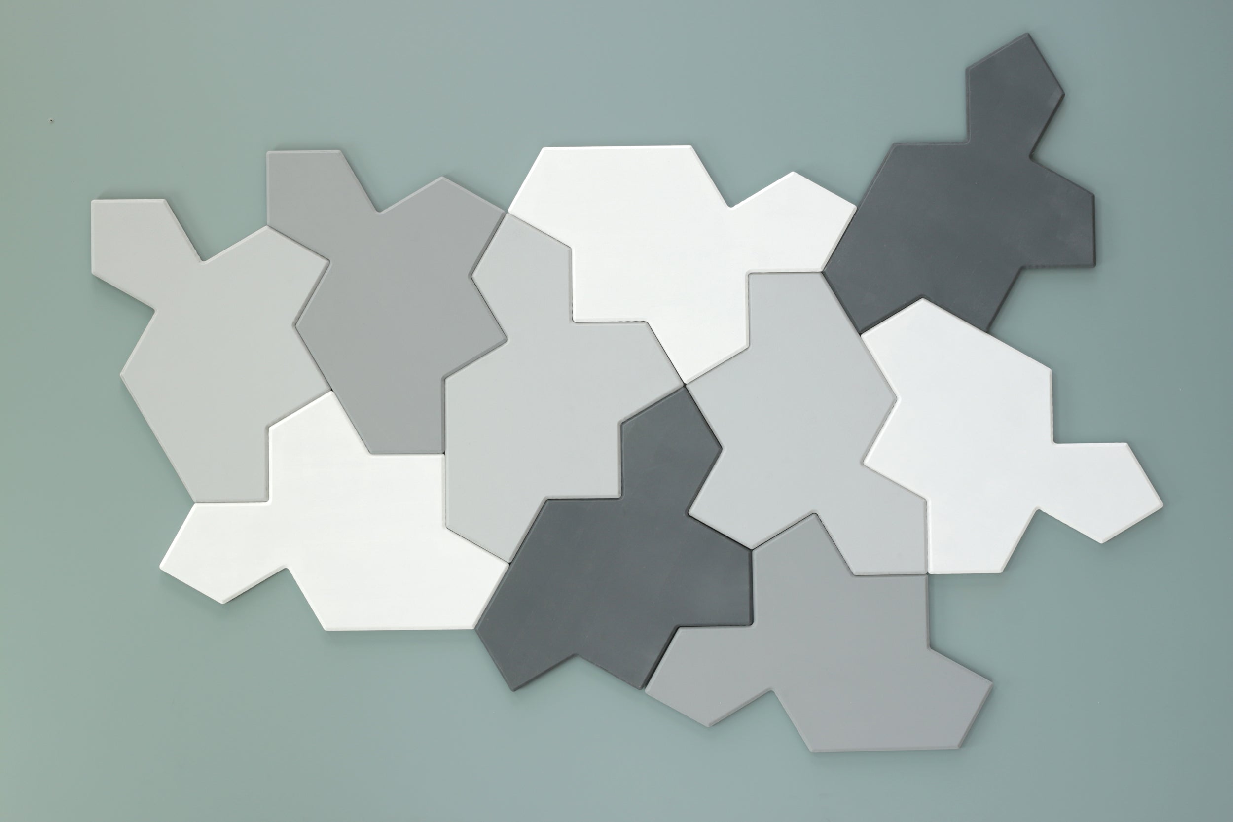 Chiral aperiodic monotile tiles in gray and white on a green  background