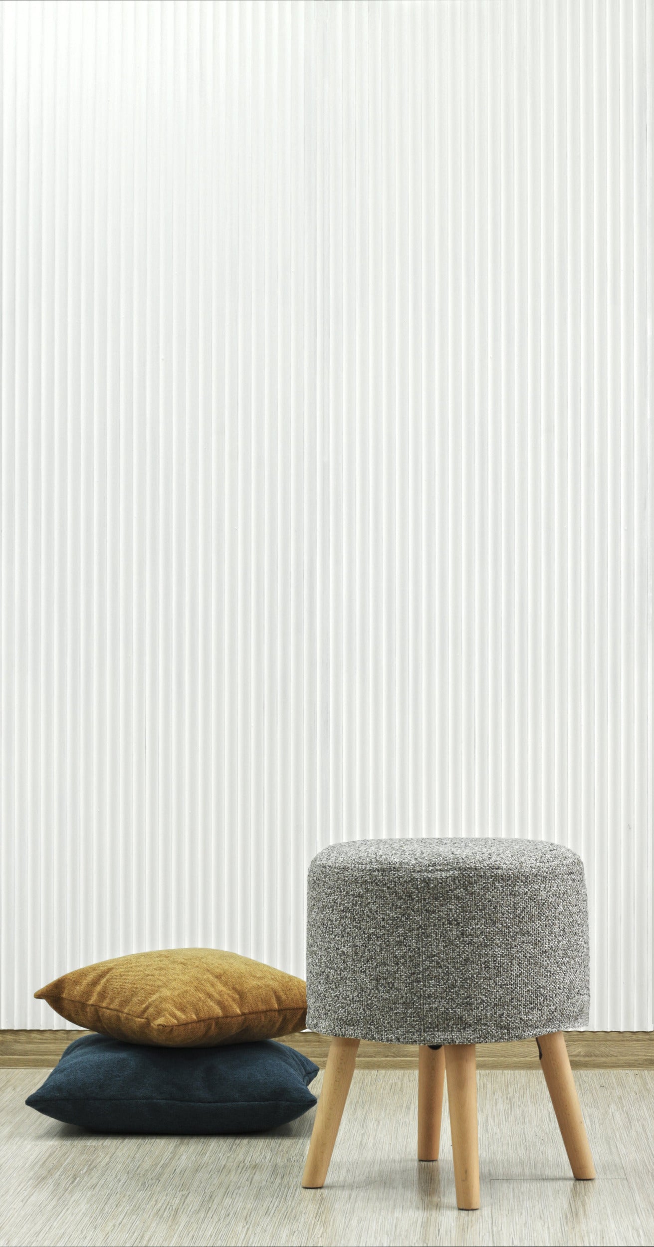 Stool Juno and two pillows against a decorative milled, white painted MDF wall with striped geometric pattern.