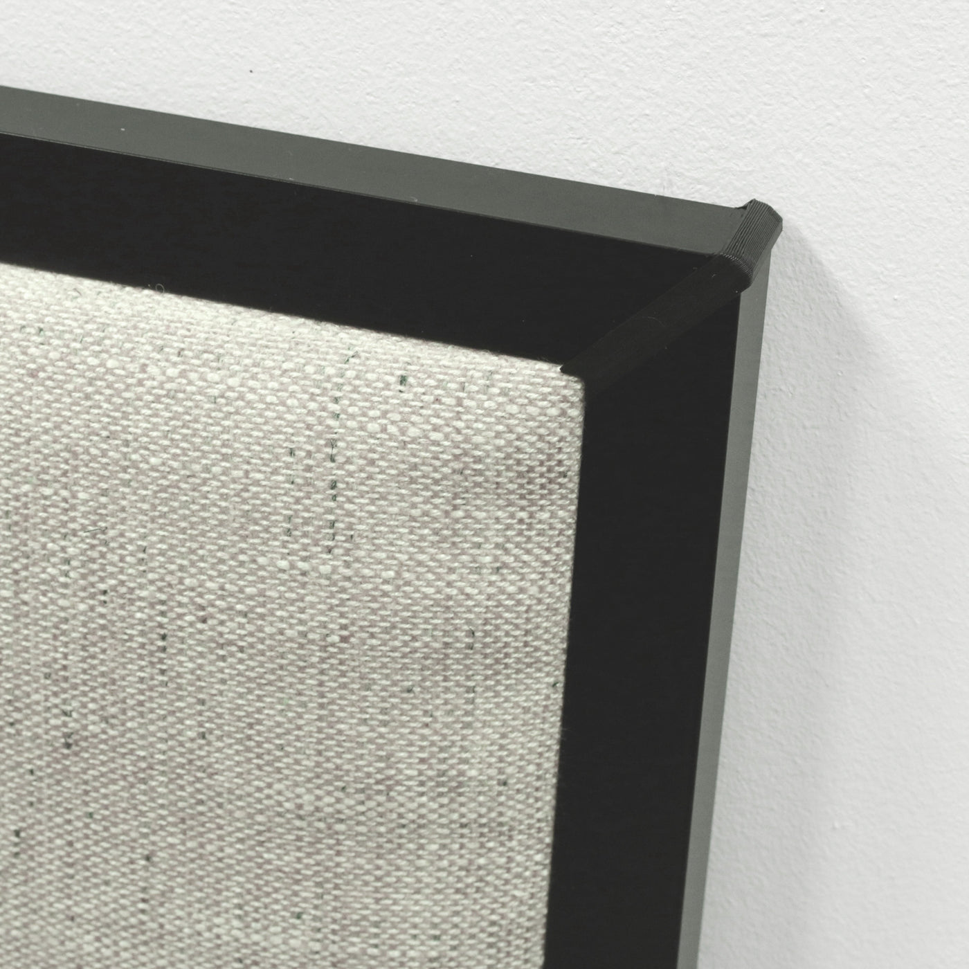 Close-up of a  headboard with a beige upholstery and black frame on a light gray background.