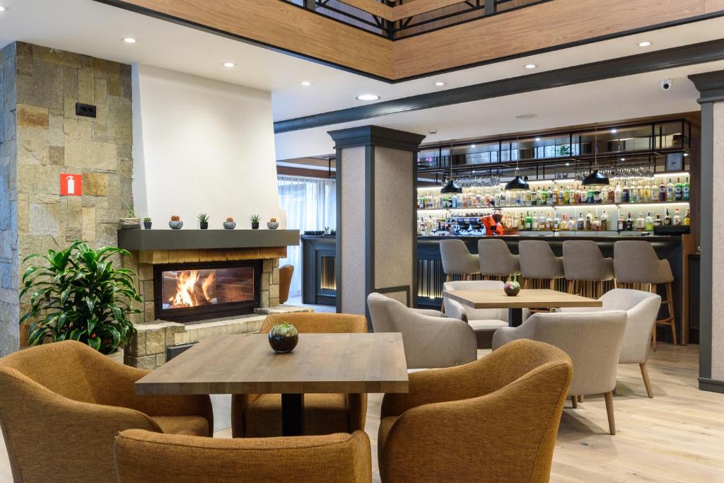Modern hotel interior with a fireplace, tables, Juno armchairs, and a bar area.