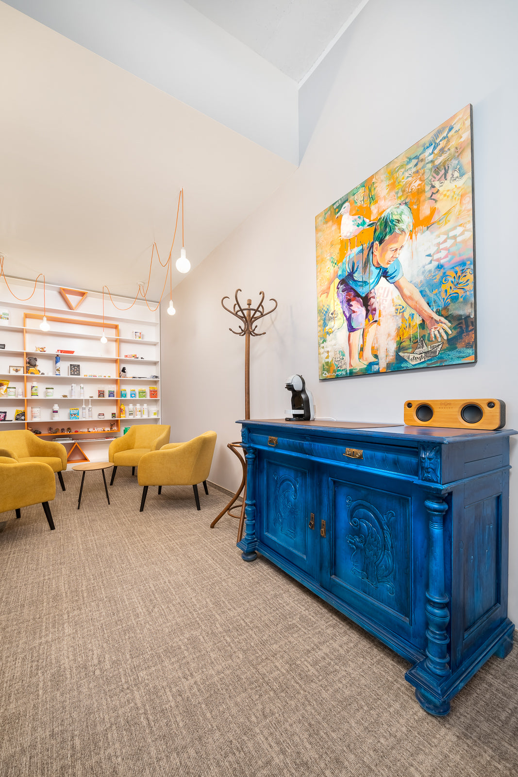 Modern interior with a blue console table, yellow Juno chairs, and a colorful painting on the wall.