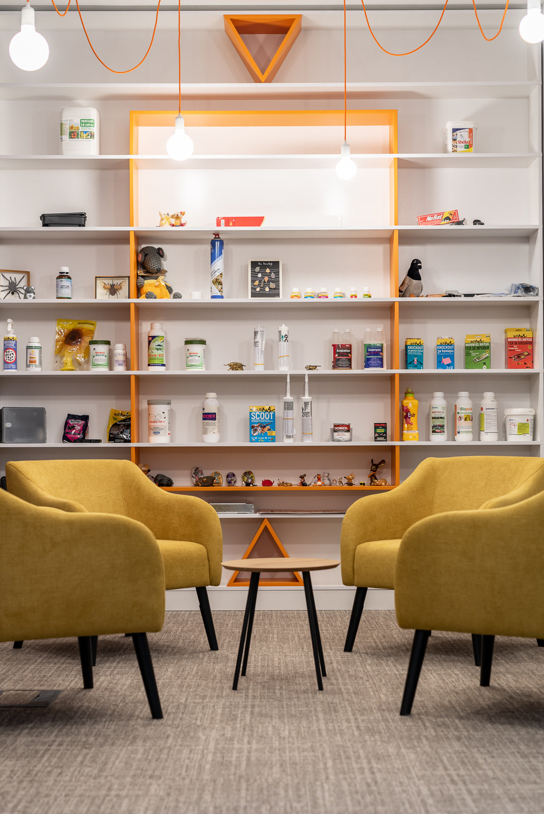 Modern office waiting area with yellow Juno chairs, shelves, and decorative items.