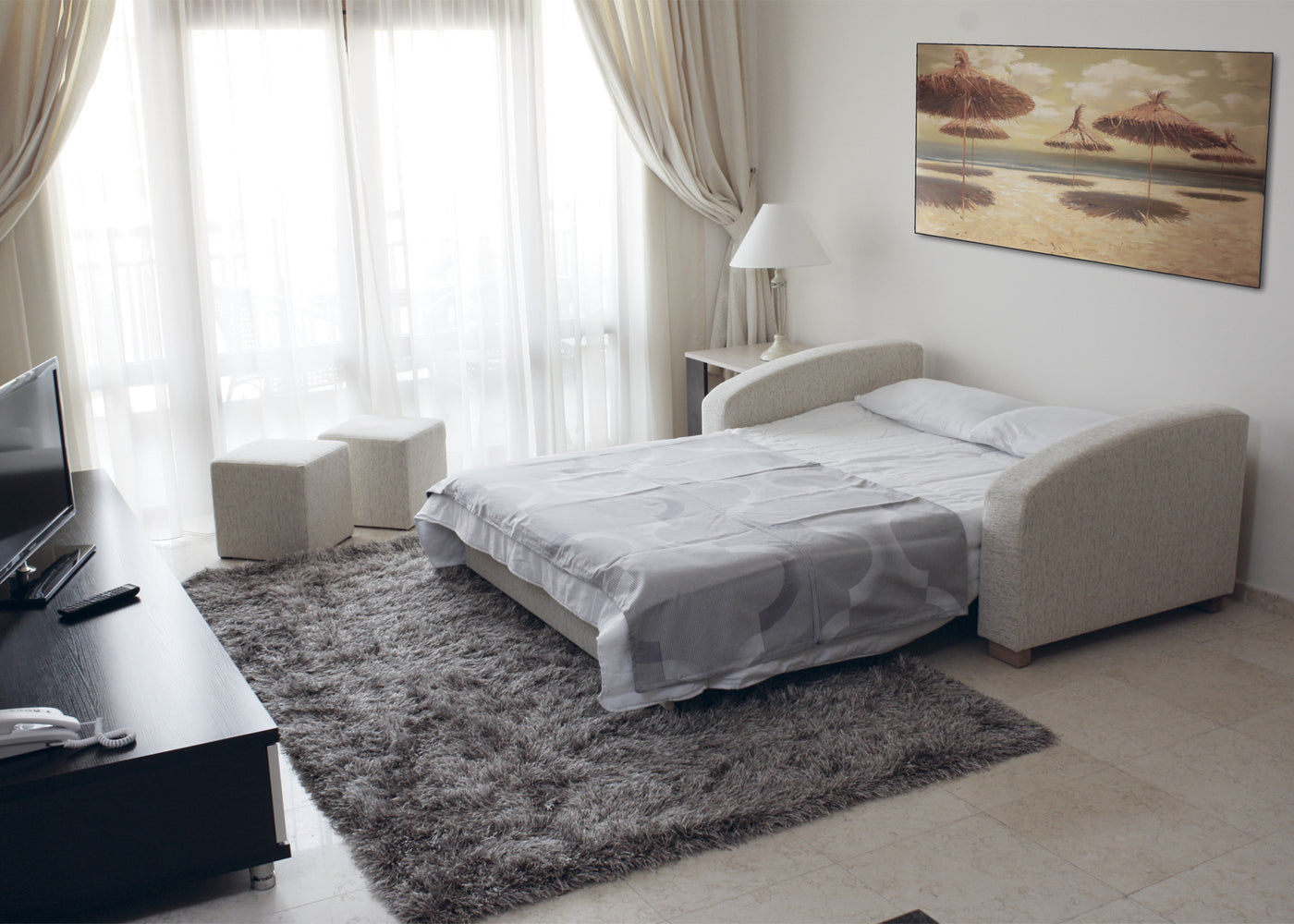 Modern hotel bedroom with a extended MAX sofa bed, TV, and decor elements.
